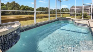 Una piscina con agua cristalina azul, rodeada por una zona techada con grandes ventanales.