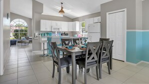 Una cocina moderna con armarios blancos, una mesa de comedor con sillas y vistas al exterior a través de un ventanal grande.