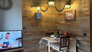 A dining area with a wooden wall, a clock, and a television displaying a chef.