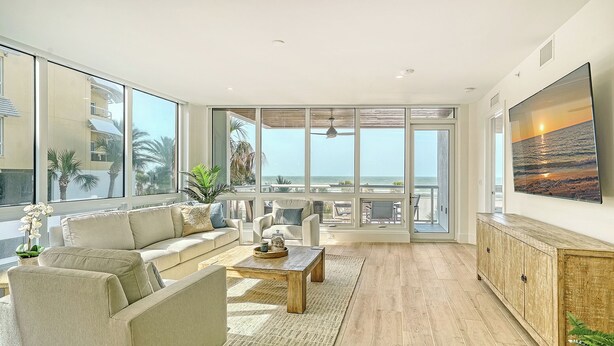 Een ruime woonkamer met een groot raam met uitzicht op de oceaan, een comfortabele bank, een salontafel en een houten kast.