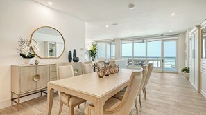 A dining area with a large table, chairs, a cabinet, and a mirror. - Beathtaking Costal Luxury with Direct Beach and Gulf Views: Residence 405 (Siesta Key)