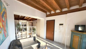 Un salón moderno con un sofá de cuero negro, techo de madera y un televisor sobre un mueble.