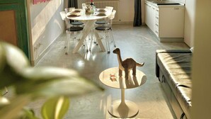 Habitación compacta con mesa de comedor, sillas, un pequeño sofá, televisión y zona de cocina.