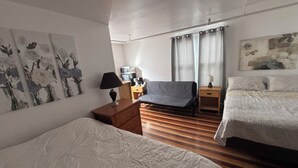 A hotel room with a bed, a sofa, a desk with a lamp, a microwave, and a painting on the wall.