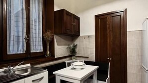 A compact kitchen with a white countertop, a sink, a dining table with chairs, and a hanging light fixture. - da mario in florence guesthause (Florence)
