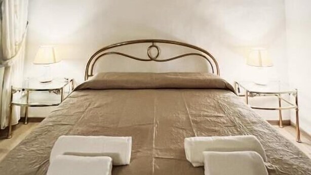 A bedroom with a bed, two bedside tables, a nightstand, a painting on the wall, and a window with curtains. - da mario in florence guesthause (Florence)