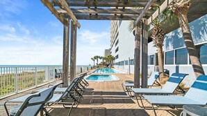 Ein Poolbereich mit Liegestühlen und Blick auf das Meer.
