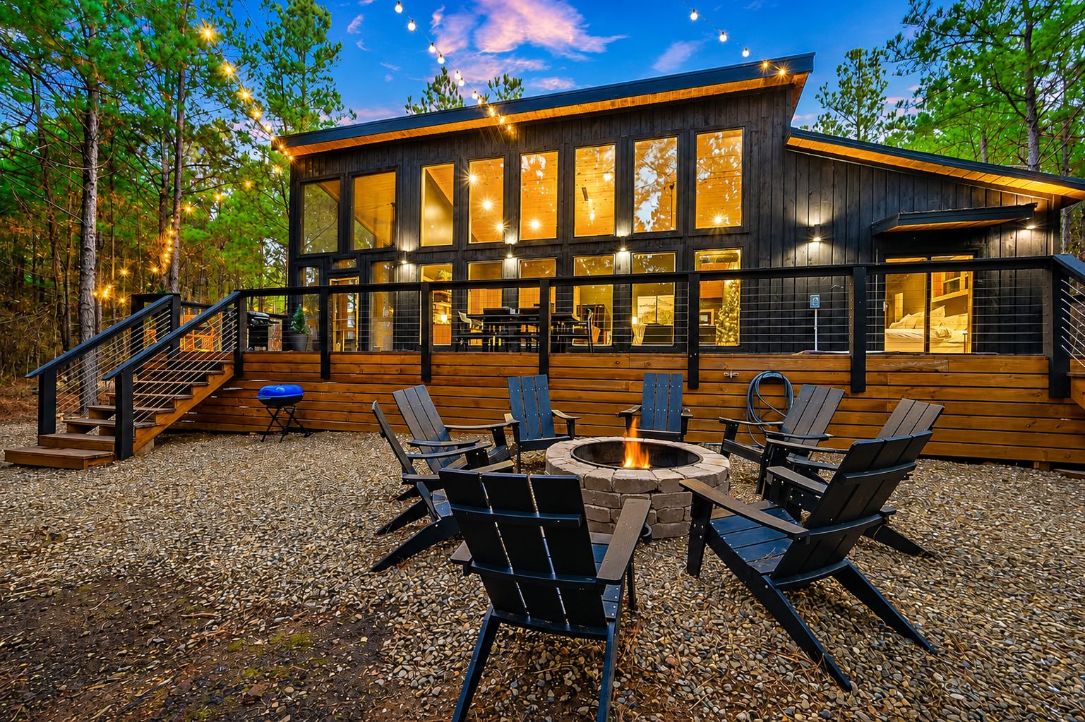 A wooden cabin with a deck, outdoor seating, and a fire pit.