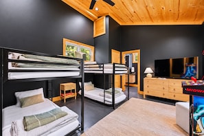A room with bunk beds, a television, a wooden cabinet, and a ceiling fan. - Swim & Recharge | Heated Pool Spa | Pool Table (Broken Bow)