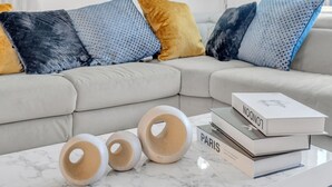 Una sala de estar con sofá, cojines estampados y una mesa de centro con libros y cuencos decorativos.
