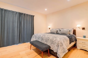 A bedroom with a bed, bedside tables, a bench, and a curtain.