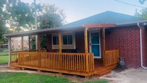 A single-story brick house with a wooden deck and a covered porch.