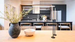 A modern kitchen with a central island, wooden chairs, a vase with branches, and a candle holder. - Tremblant Prestige - Verbier 4-202 (Mont-Tremblant)