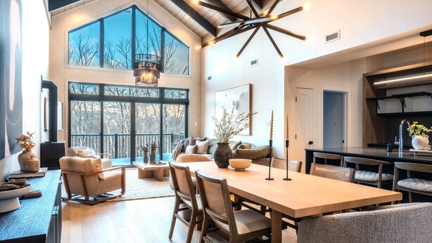A spacious living area with a large wooden dining table, comfortable seating, and a view through large windows. - Tremblant Prestige - Verbier 4-202 (Mont-Tremblant)