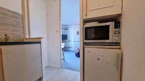 Cuina estreta amb microones i nevera, que connecta amb una zona d'estar.