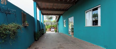 A narrow, covered corridor with teal walls, a concrete floor, and a wooden ceiling.