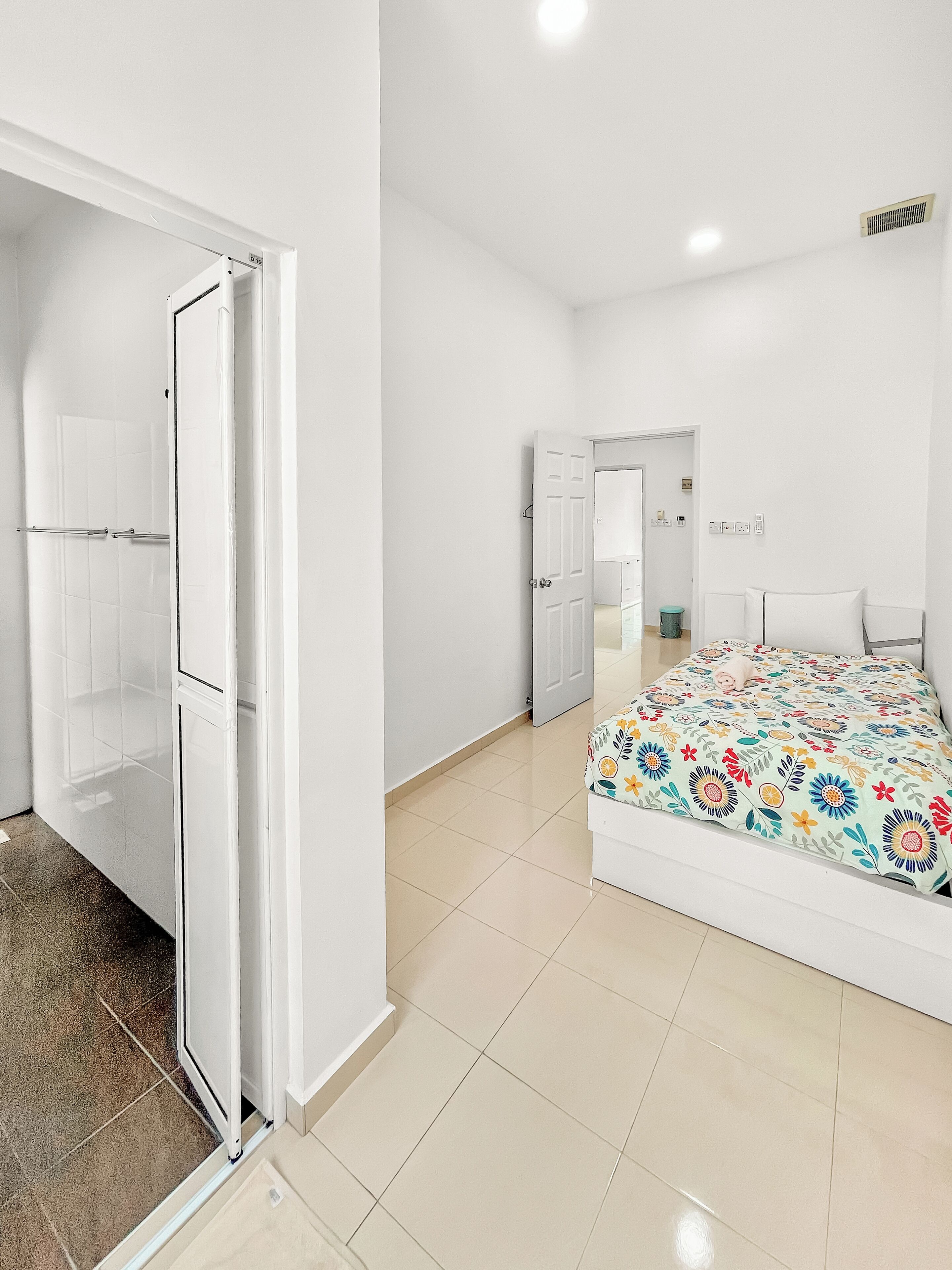 Ein modernes Schlafzimmer mit Bett, Duschbereich und begehbarem Kleiderschrank.