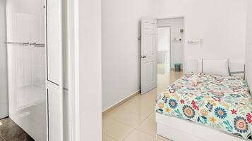 Ein modernes Schlafzimmer mit Bett, Duschbereich und begehbarem Kleiderschrank.