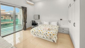 A modern bedroom with a large bed, a desk, and a chair, featuring a sliding glass door to a balcony. - 4 Bedroom Landed House (Batu Pahat)