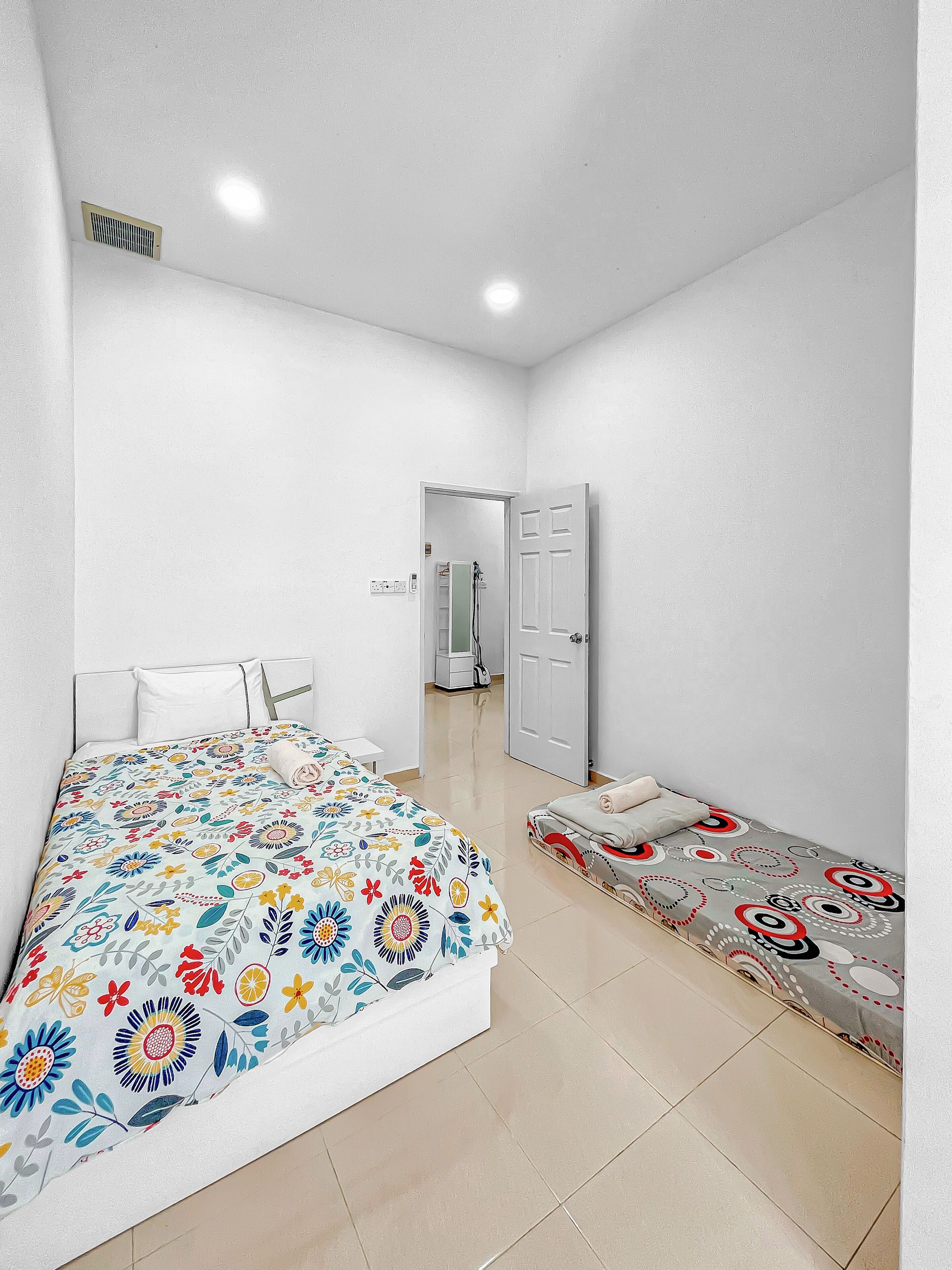 Una camera da letto con un letto, un comodino, una sedia, un armadio e una porta che dà su un'altra stanza.