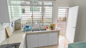 A modern kitchen with a central island, a stove, and a sink. - 4 Bedroom Landed House (Batu Pahat)