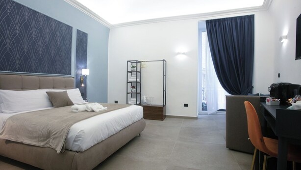 A modern hotel room with a large bed, a desk, and a seating area. - PIGNASECCA DOMUS (Naples)