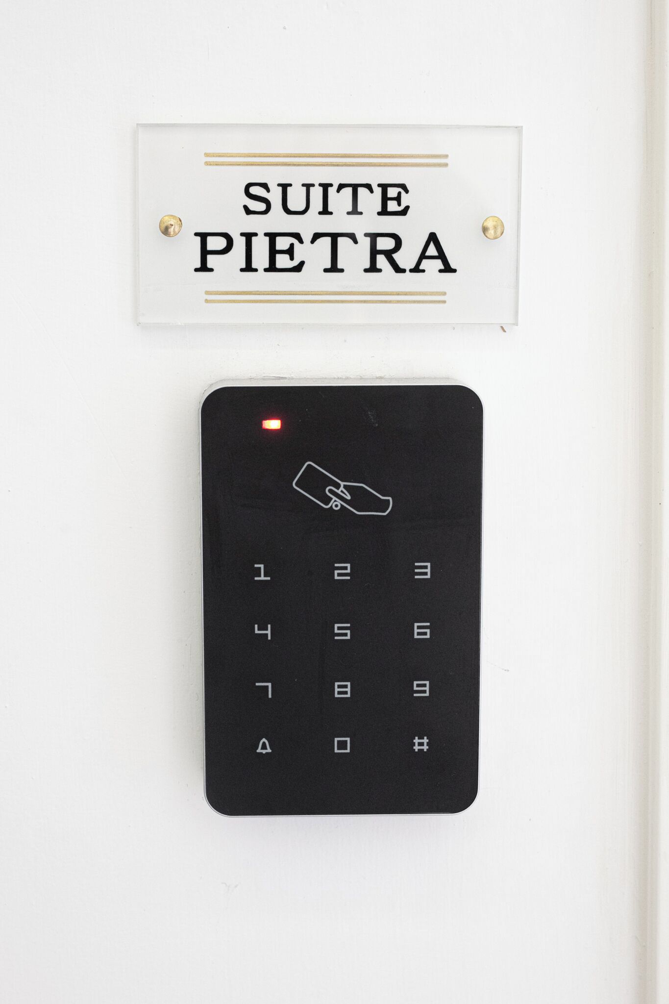 A sign reading "SUITE PIETRA" and a keypad with a hand icon.