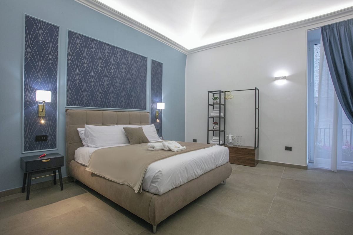 Un dormitorio con una cama grande, mesitas de noche, un espejo y vistas al exterior.