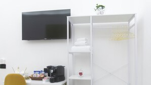 A room with a white desk, a yellow chair, a black suitcase, a white wardrobe, and a flat-screen TV mounted on the wall. - PIGNASECCA DOMUS (Naples)