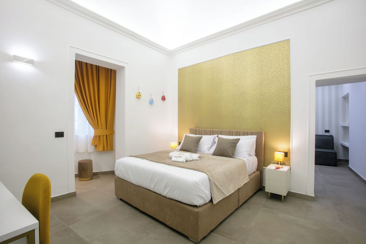 Una habitación de hotel moderna con una cama grande, mesitas de noche, un escritorio y una silla.