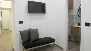 A modern, minimalist room with a black sofa, a mounted TV, and a wooden cabinet in the background. - PIGNASECCA DOMUS (Naples)