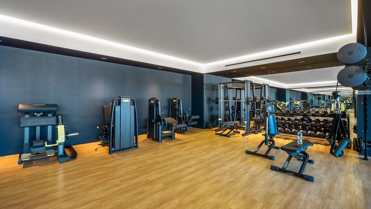 Un gimnasio con diversos equipos de ejercicio, incluyendo máquinas de pesas, pesas libres y máquinas de cardio.