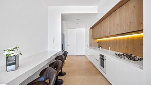 Una cocina moderna con armarios blancos, encimera de madera y estufa integrada.