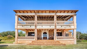 Un immeuble de deux étages avec une façade en pierre, une entrée centrale et un balcon à chaque étage.