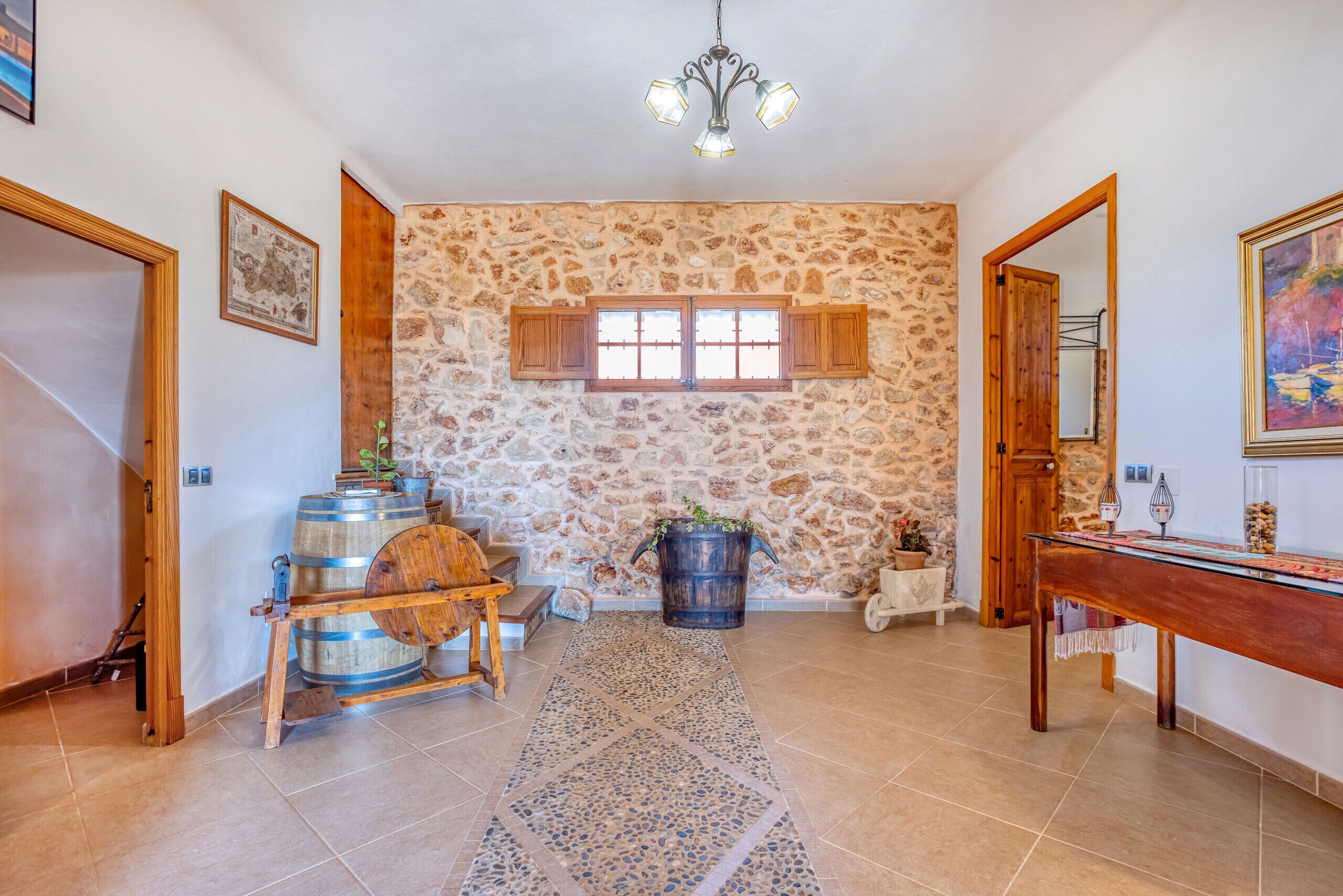 Un interior rústico con paredes de piedra, barriles de madera, un candelabro y una mesa de madera.