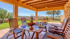 An outdoor patio with wooden furniture, a fruit bowl, and a view of the landscape. - Na Corme Nova by dracmallorca (Calonge)