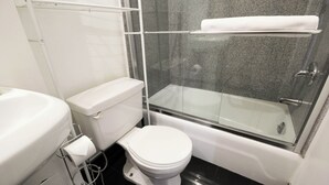 A modern bathroom with a toilet, a glass-enclosed shower, and a white sink.