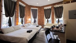 A hotel room with two beds, a desk, a chair, and a window with curtains.