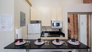 A compact kitchen with a dining area, equipped with a refrigerator, microwave, and sink.