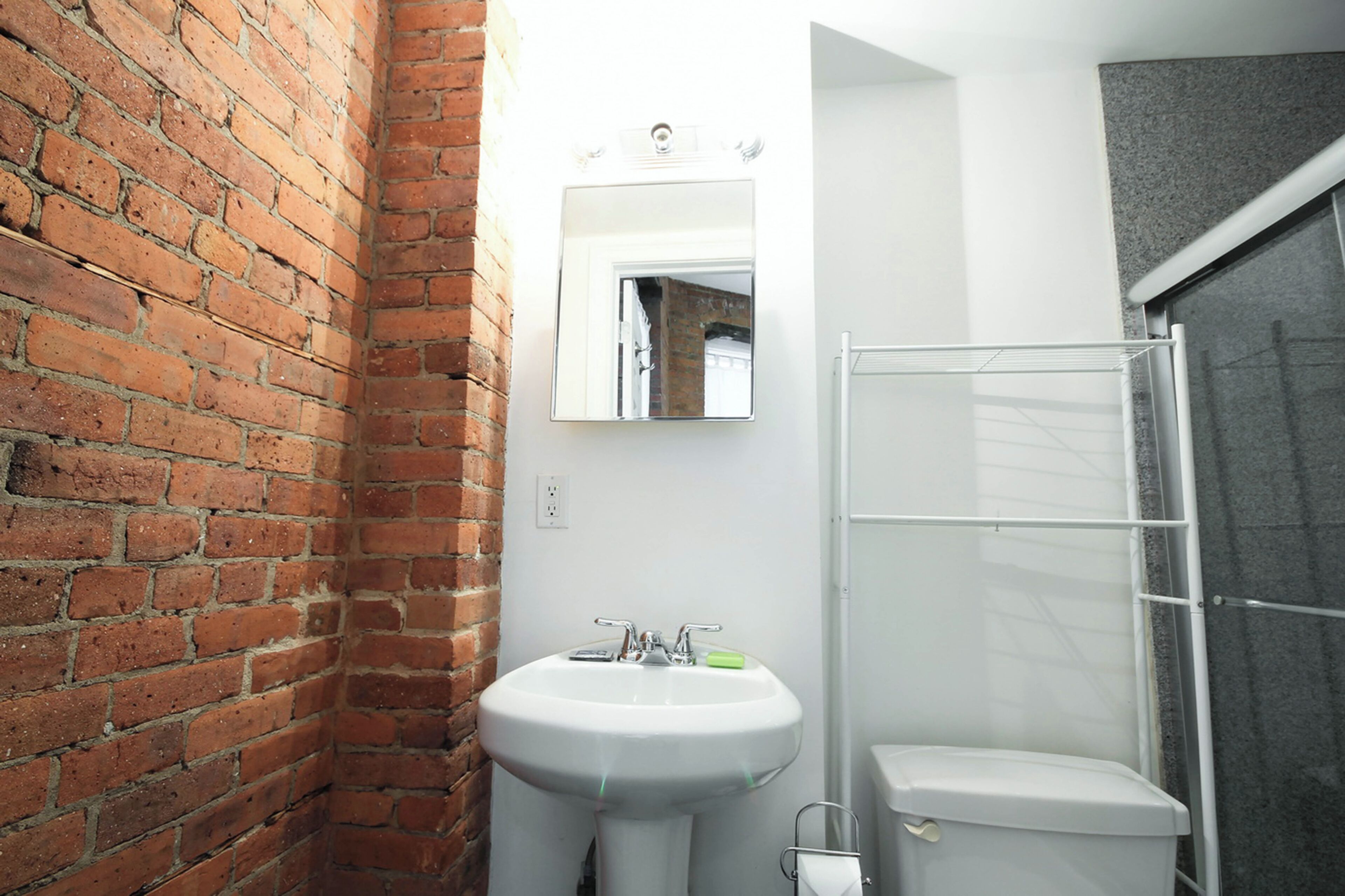 A bathroom with a white sink, a mirror, and a shower area.