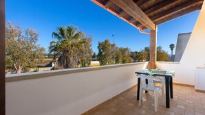 A balcony with a table and chairs, a view of trees and a clear sky. - Casa Ariel - Relaxation for couples near the beach (torre san giovanni)