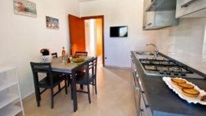 A compact kitchen with a dining area, a stove, and a small table. - Casa Ariel - Relaxation for couples near the beach (torre san giovanni)
