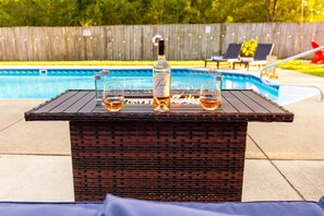 A poolside table with a bottle and glasses. - Pool & Play | Hot Tub, Ping Pong, Nintendo Switch (Stevensville)