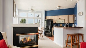 A modern kitchen with a central island, wooden cabinets, and a built-in microwave. - Main Floor, Easy Access Water View Condo (Manistee)