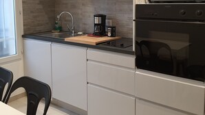 A modern kitchen with white cabinets, a black countertop, a coffee maker, and a microwave.
