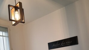 A bedroom with a wooden headboard, a bed with a light-colored sheet, a wall-mounted sign, and a hanging light fixture.