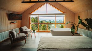 Ein Schlafzimmer mit großem Fenster, einer Badewanne und zwei Sofas.