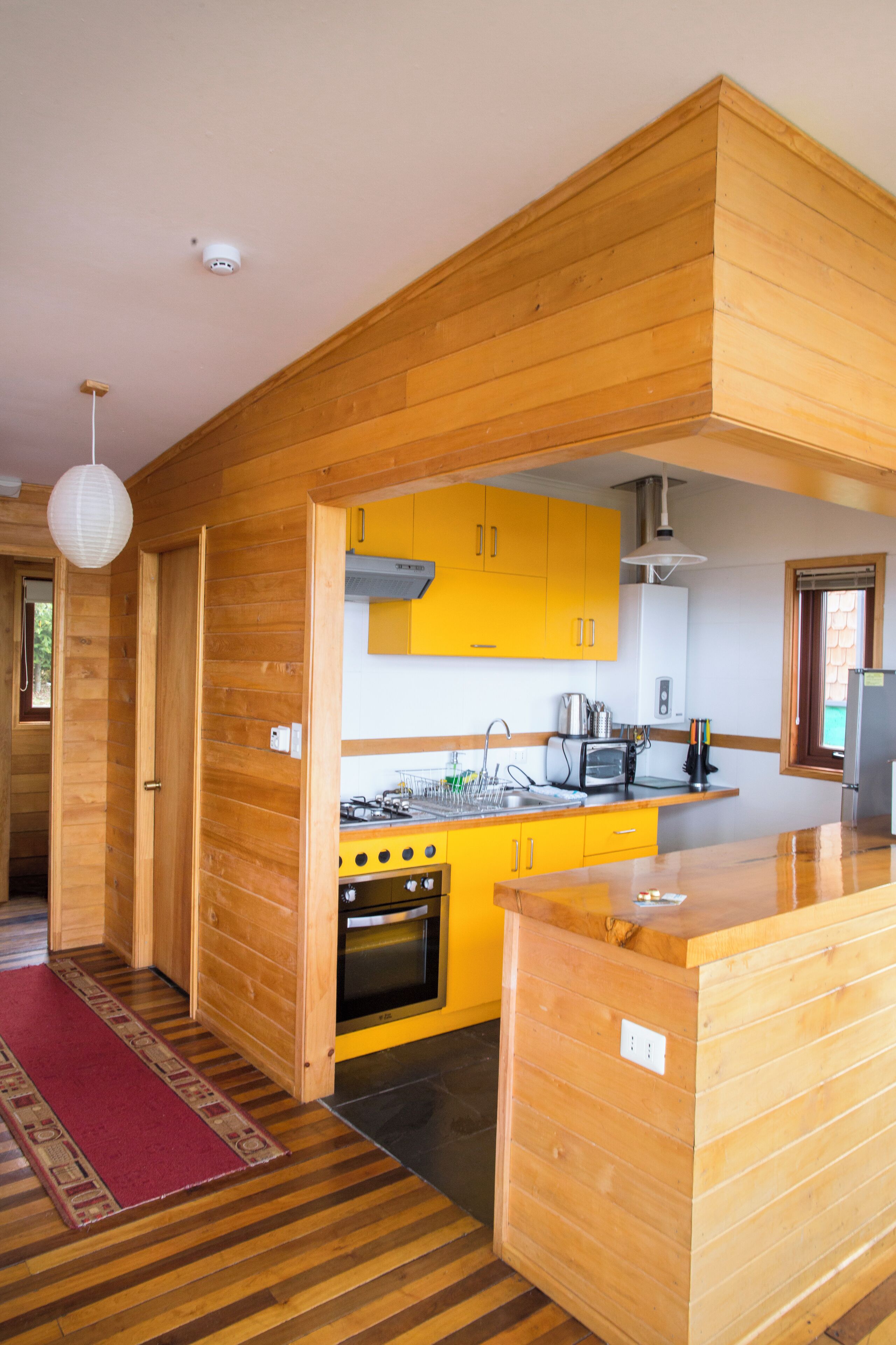 Une cuisine moderne avec des murs en bois, des armoires jaunes et un îlot central.