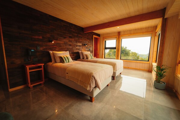 Un dormitorio moderno con dos camas, una pared de madera, una mesita de noche pequeña y un ventanal grande.
