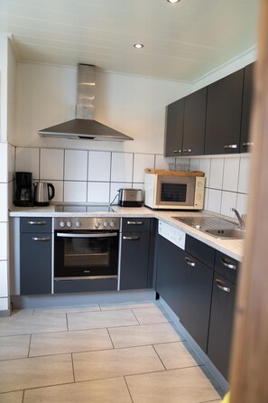 Kitchen features a stainless steel range hood, oven, microwave, and toaster.
